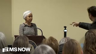 A man sprays liquid on Representative Ilhan Omar during an event in Minnesota